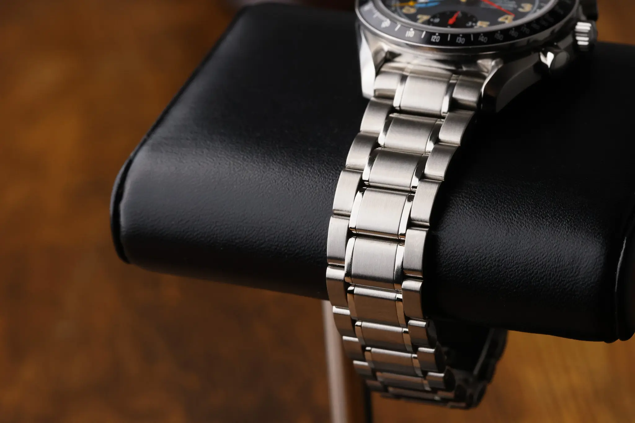 Omega Speedmaster Day Date bracelet photographed on a black leather cushion