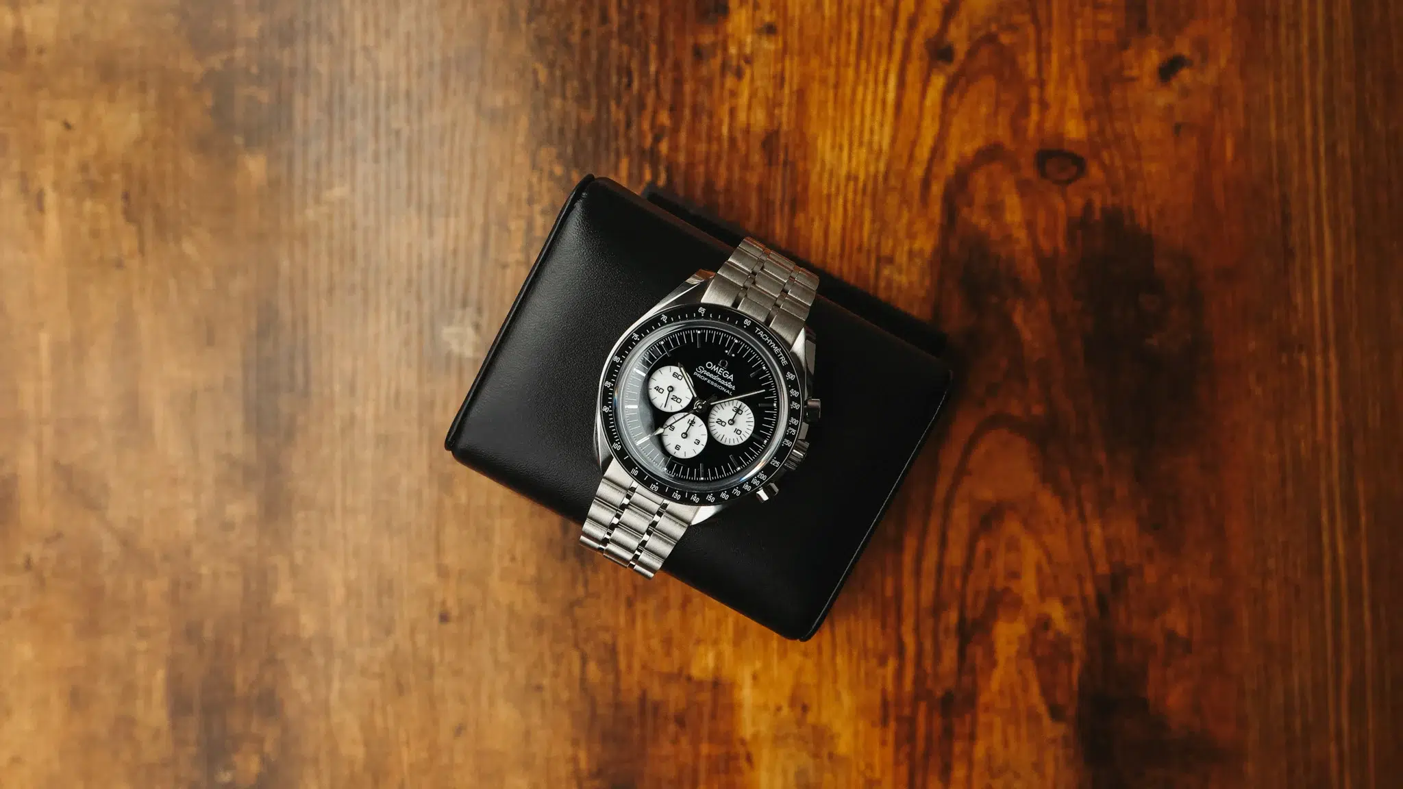 Omega Speedmaster Moonwatch Professional chronograph on stainless steel bracelet photographed from above on a wooden surface