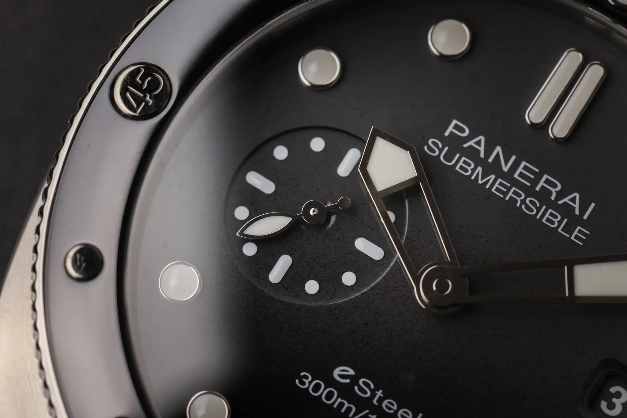 Panerai Submersible QuarantaQuattro Grigio Roccia PAM01288 photographed from above on a black stand with warm wood background