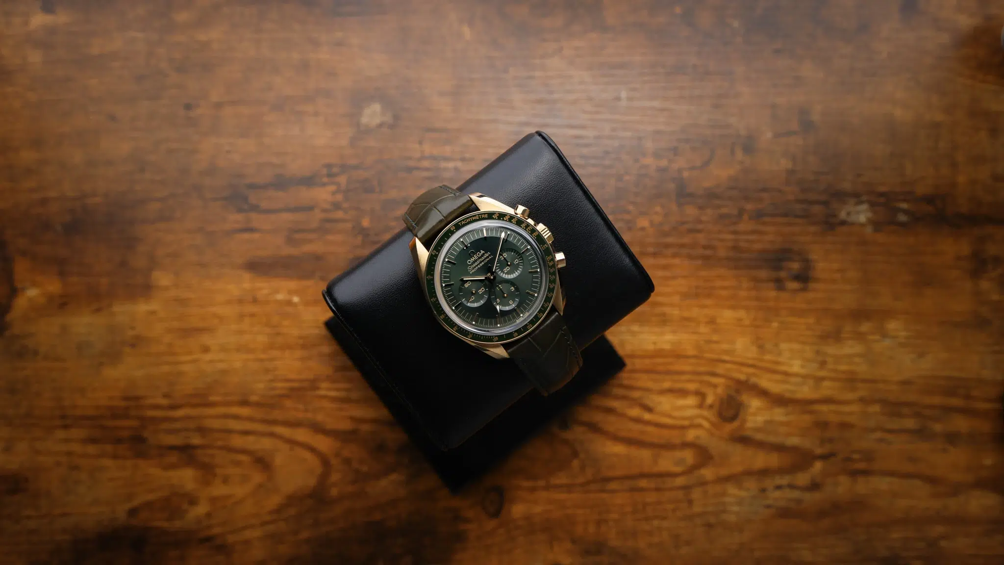 Omega Speedmaster Moonwatch Professional 18K Yellow Gold 310.63.42.50.10.001 displayed on leather watch stand